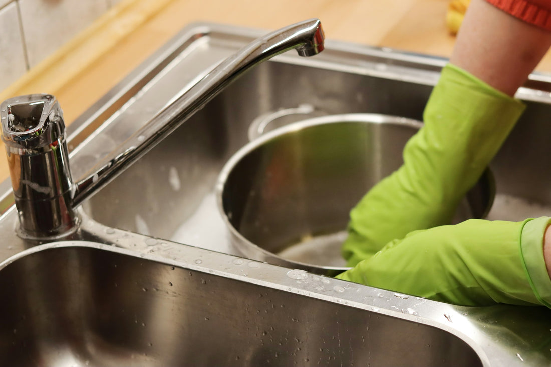 Realistic editorial lifestyle scene showing dish brush vs sponge vs silicone scrubber in active household use, practical