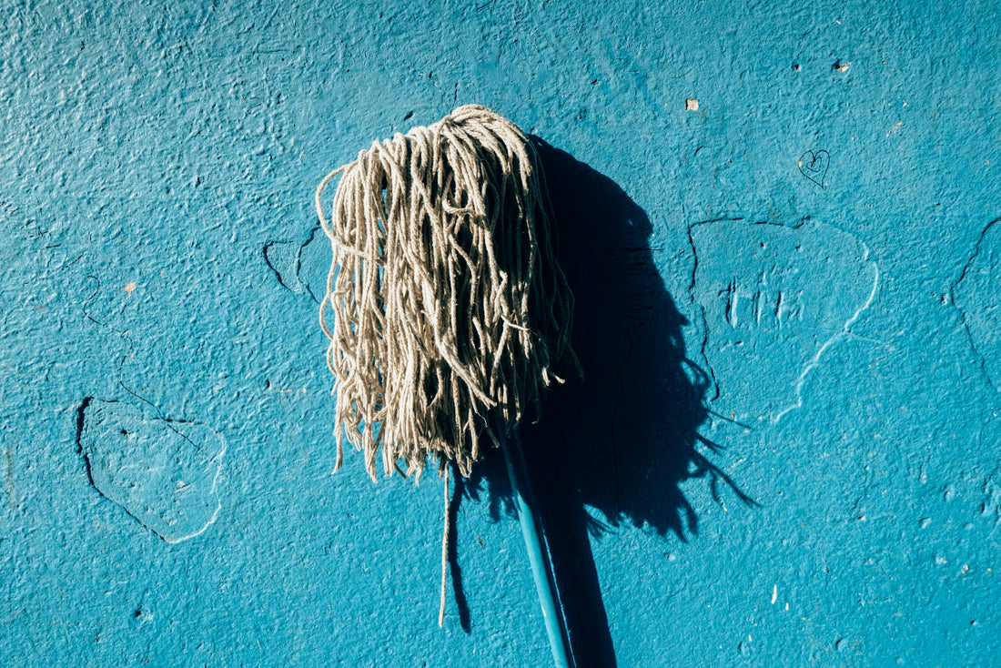 A mop head against a plain blue wall
