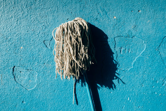 A mop head against a plain blue wall