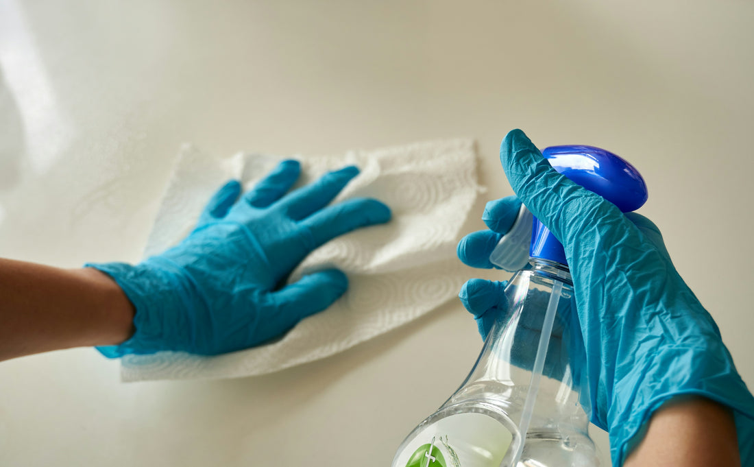 A person wiping a surface with a cloth and spray bottle