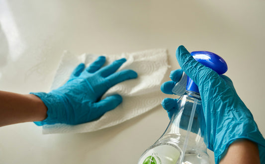 A person wiping a surface with a cloth and spray bottle