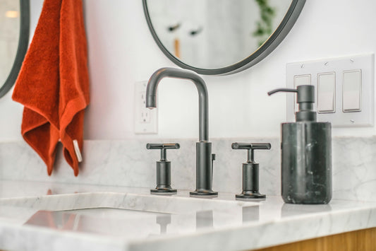 Realistic editorial lifestyle scene showing plunger vs drain snake in active household use, practical uncluttered settin