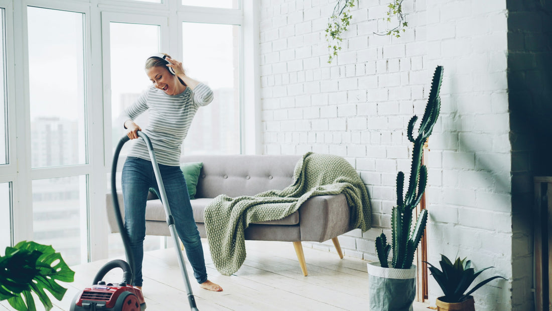 A person vacuuming a hardwood living room floor near a couch