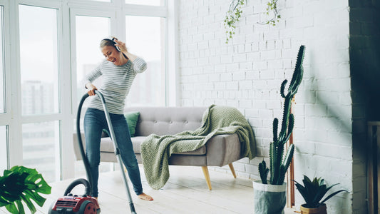 A person vacuuming a hardwood living room floor near a couch