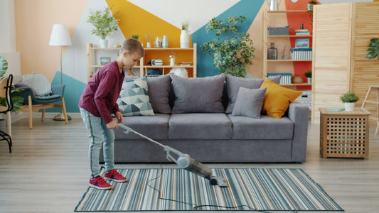 A child vacuuming a striped rug in a living room